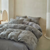 A set of Nordic leaf print duvet covers in soft gray fabric displayed on a bed against a light wall.