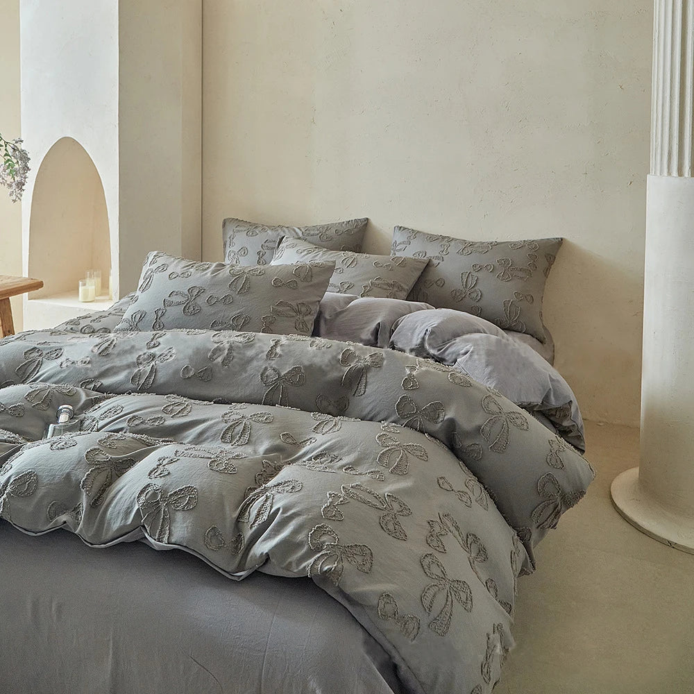 A set of Nordic leaf print duvet covers in soft gray fabric displayed on a bed against a light wall.