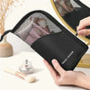 A hand holds a black waterproof makeup brush holder with a mesh cover and foldable stand on a white surface.