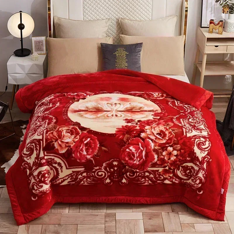 A red weighted plush blanket with a floral pattern is displayed on a bed.