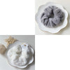A close-up of a gray plush coil hair tie resting on a white ceramic plate.