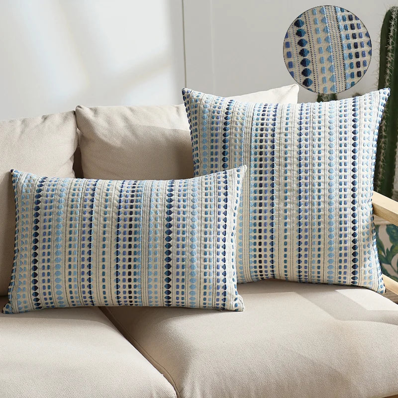 Two light blue and white patterned linen pillow covers displayed on a beige sofa.