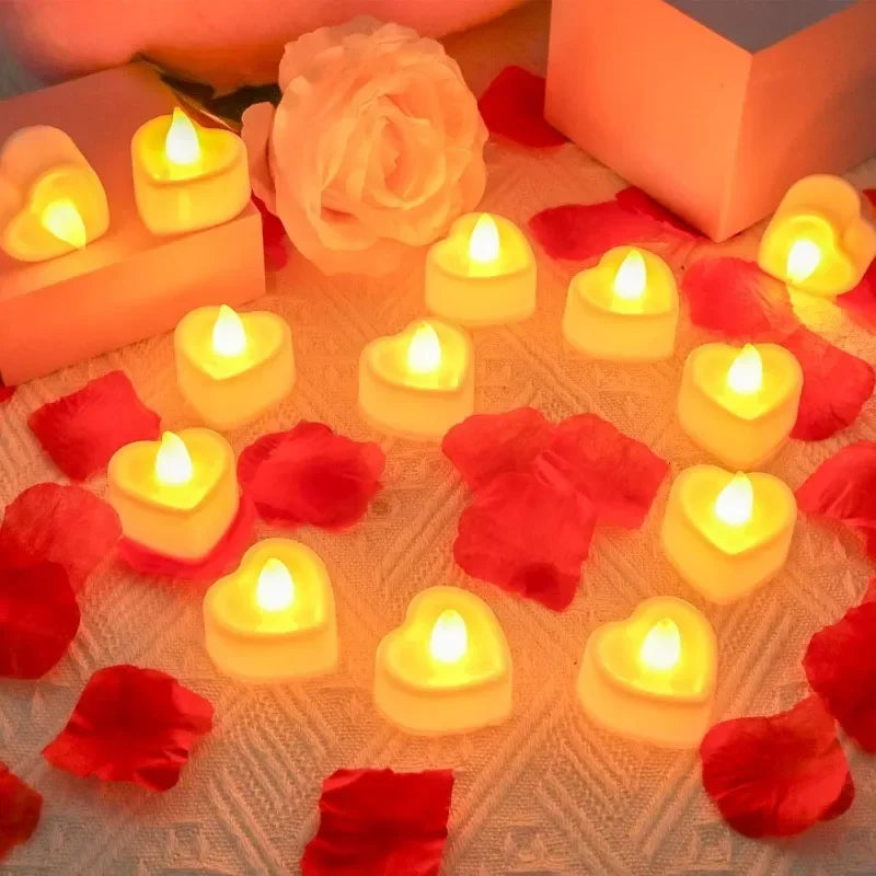 Heart-shaped flameless LED candles glowing on a surface surrounded by red rose petals.