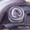 A ball of gradient grey and white yarn is displayed on a dark grey knitted fabric.