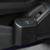 A close-up view of a portable car trash bin with a press-type lid mechanism on a dark gray surface.
