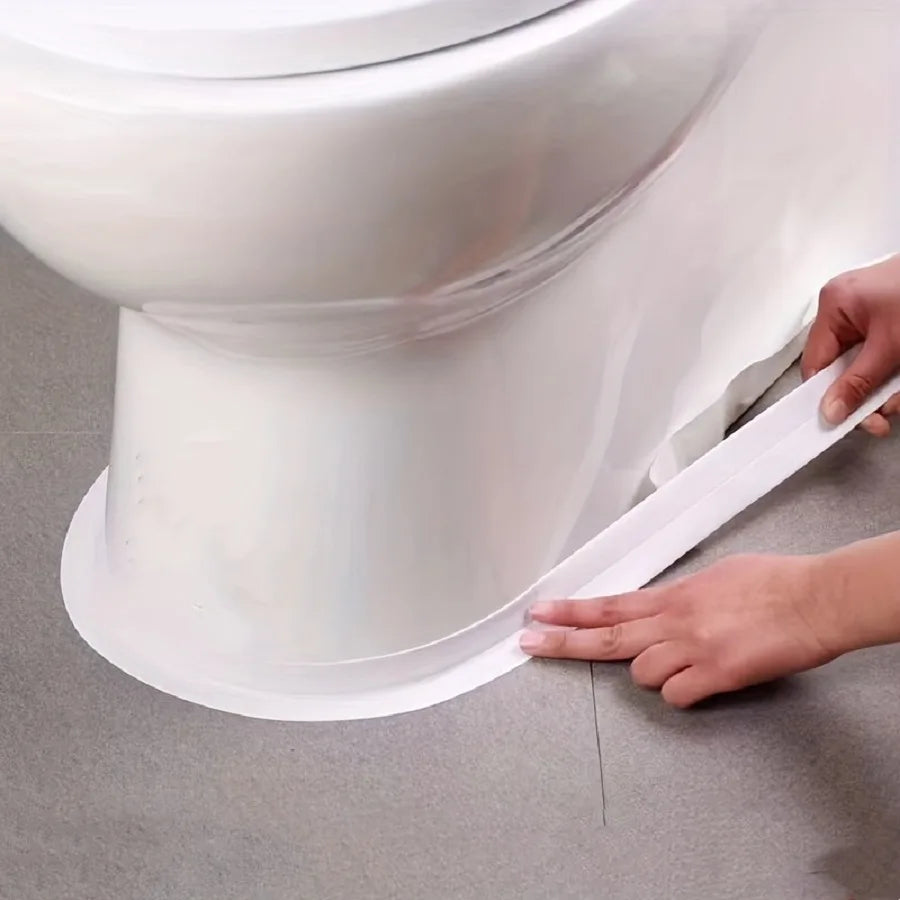 Eine Hand appliziert ein Stück weißes, selbstklebendes Silikondichtband am Sockel einer weißen Porzellan-Toilettenschüssel.