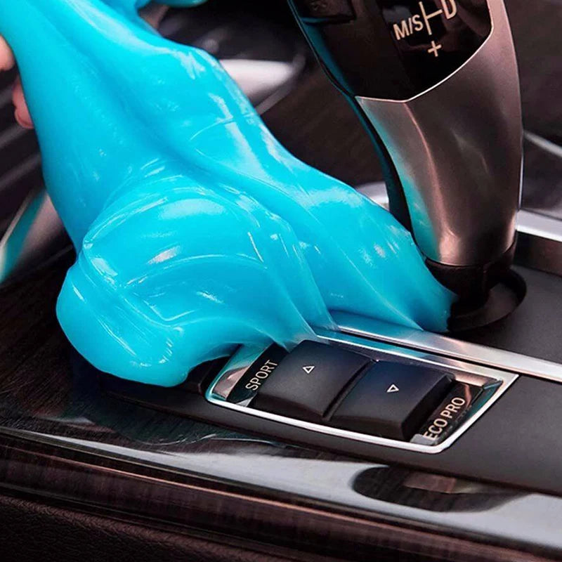 A hand wearing a bright blue reusable cleaning gel is being applied to a black electronic device.