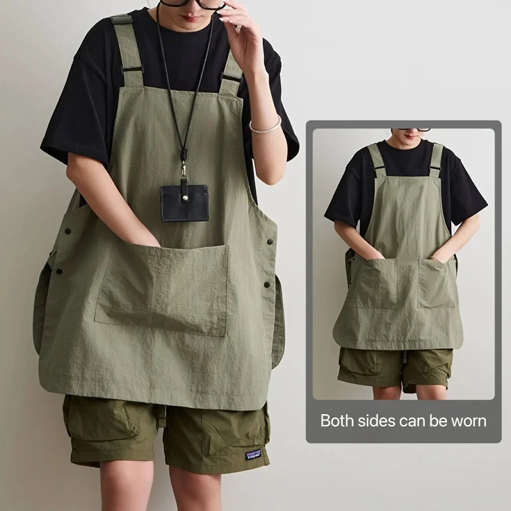 A person wearing a olive green waterproof work apron over a black shirt and shorts.