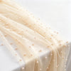 Elegant faux pearl tulle table runner in beige fabric draped on a white surface.