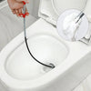 A hand is using a flexible drain snake with a wire to clear a clog in a toilet bowl.
