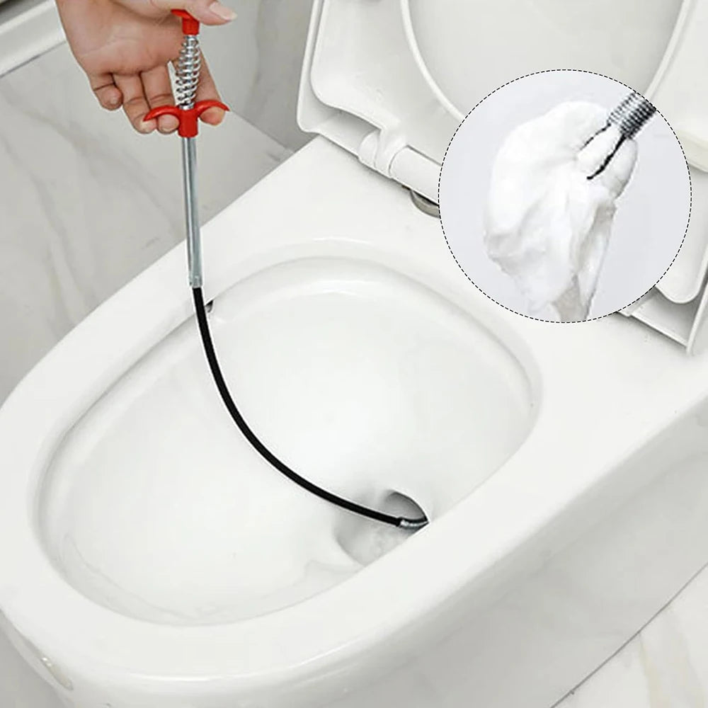 A hand is using a flexible drain snake with a wire to clear a clog in a toilet bowl.