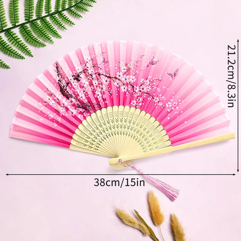 Pink and white vintage lace folding hand fan with a yellow handle displayed on a light pink background.