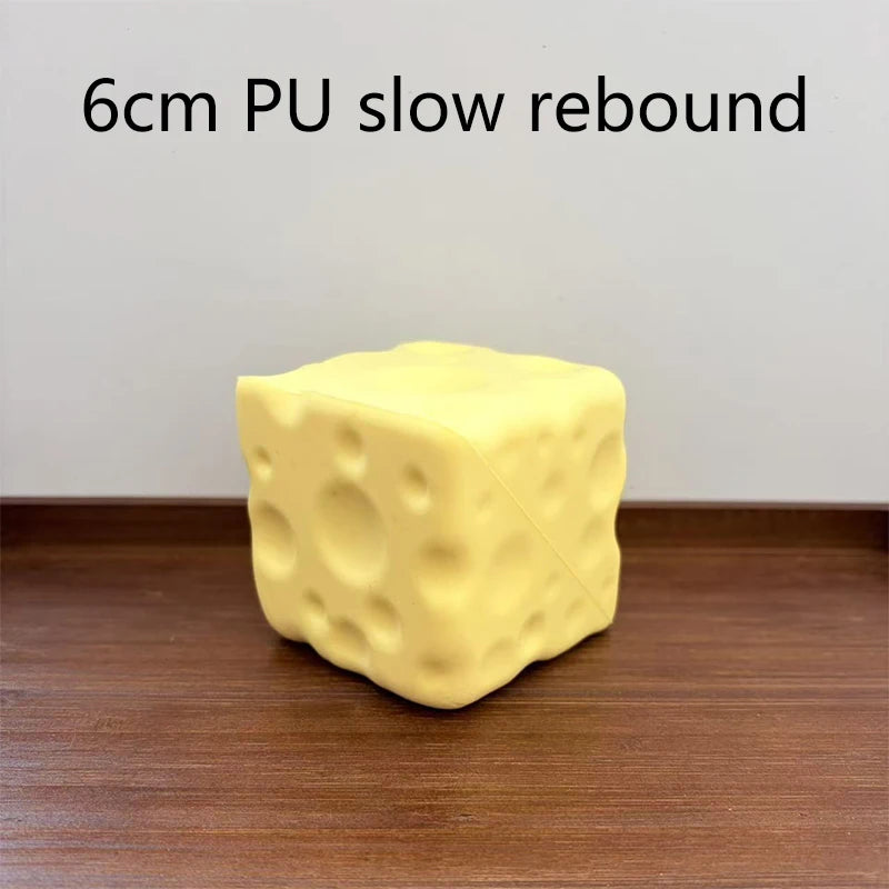 A yellow, cube-shaped PU slow rebound fidget toy resting on a wooden surface.
