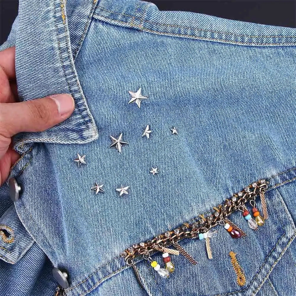 Nahaufnahme von blauem Jeansstoff mit silbernen Stern-Nieten und goldenen Kettendetails