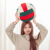A woman holds a simulation volleyball plush toy pillow with red and green stripes against a white background.
