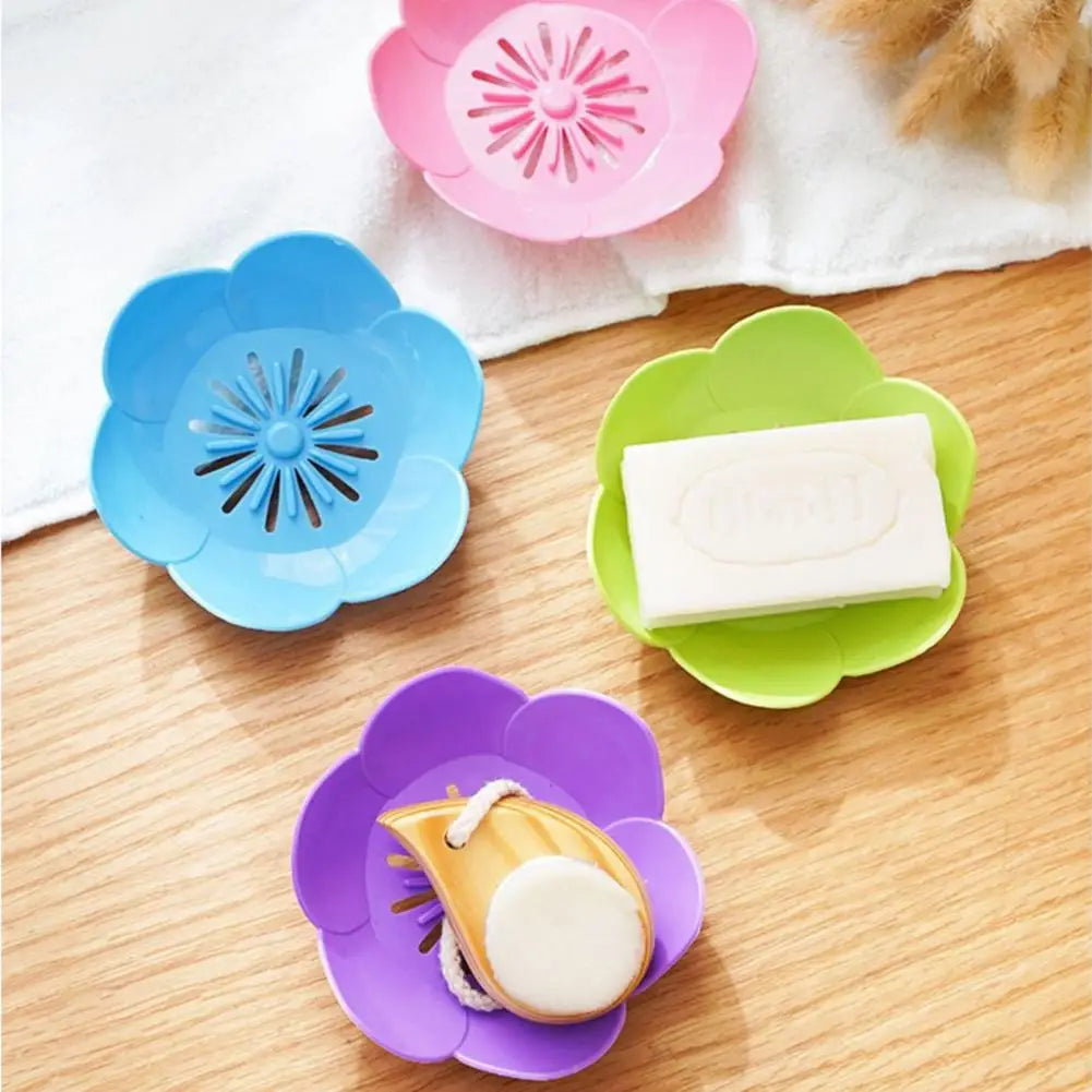 A set of colorful plastic lotus-shaped bathroom storage racks in pink, blue, and green holding white bars of soap.
