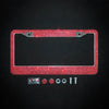 A rectangular license plate frame covered in red crystal rhinestones with mounting tabs and small accessories.