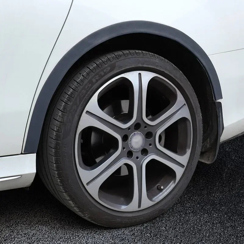 A close-up view of a white car wheel arch with a black trim and a silver alloy wheel.