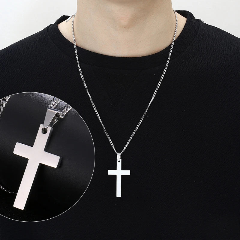 A silver stainless steel cross pendant necklace is displayed against a black shirt with a circular inset showing the pendant 