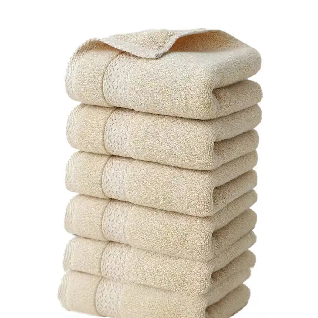 A stack of six beige premium pure cotton face towels folded neatly.