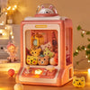 A pink mini claw crane machine for kids with lights and music is displayed on a wooden surface.