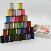 A stack of 64 colored sewing threads in spools, arranged vertically on a white surface.