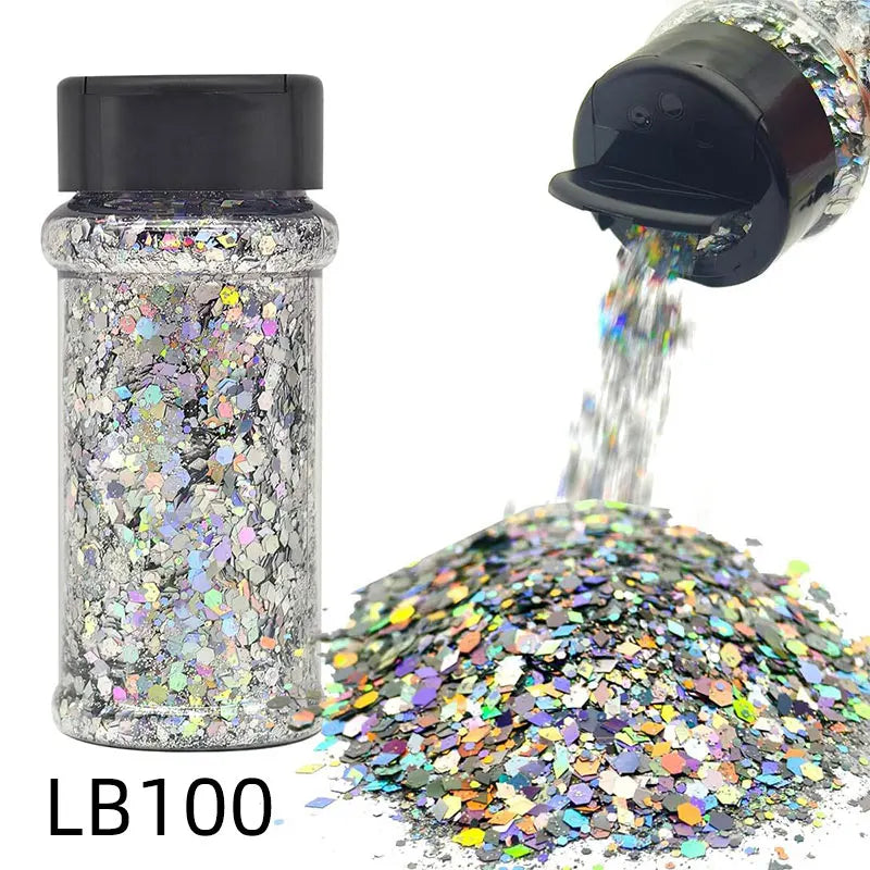 A glass jar of holographic chunky nail glitter mix with a shaker top next to a pile of the same glitter.