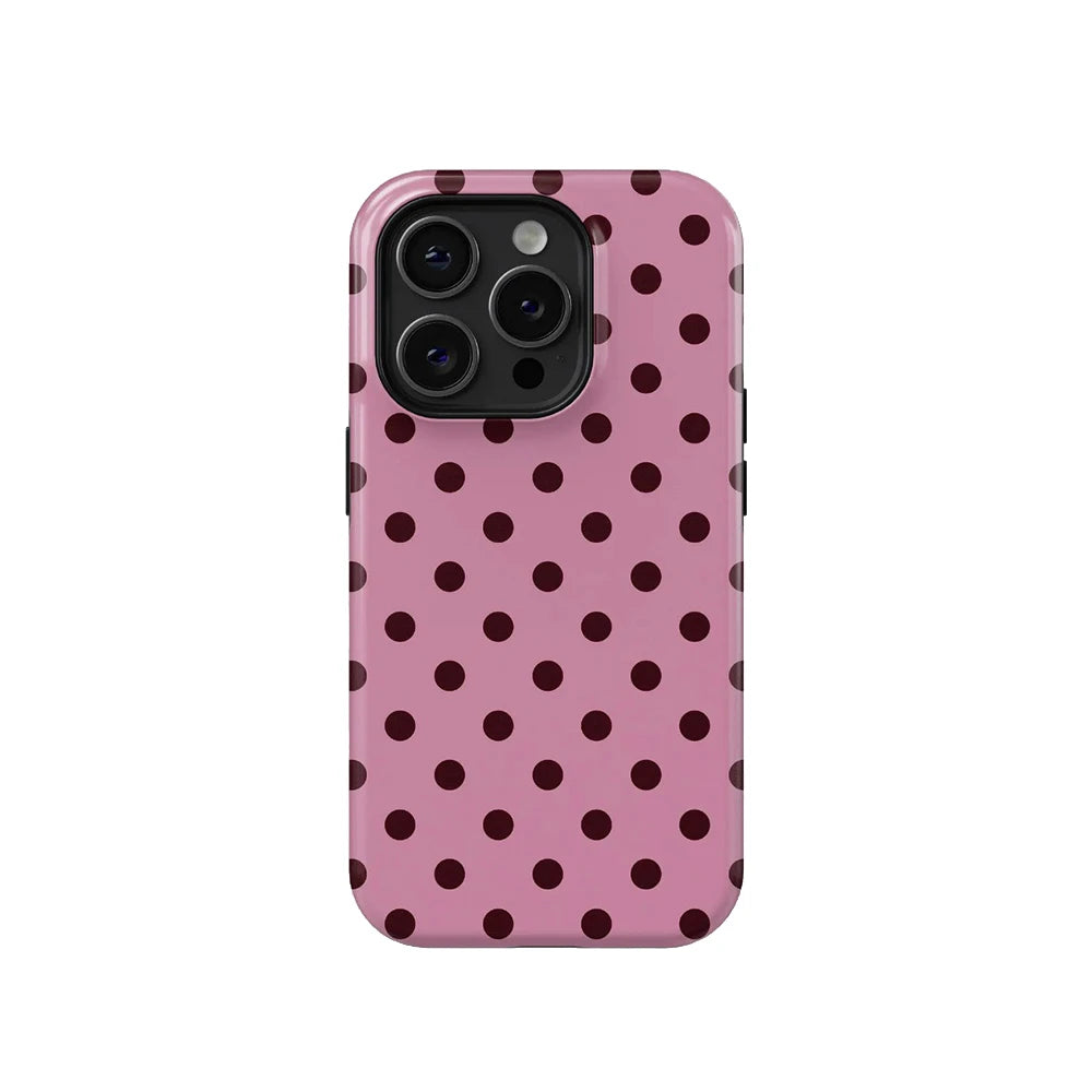 A pink phone case with a dark polka dot pattern for an iPhone.