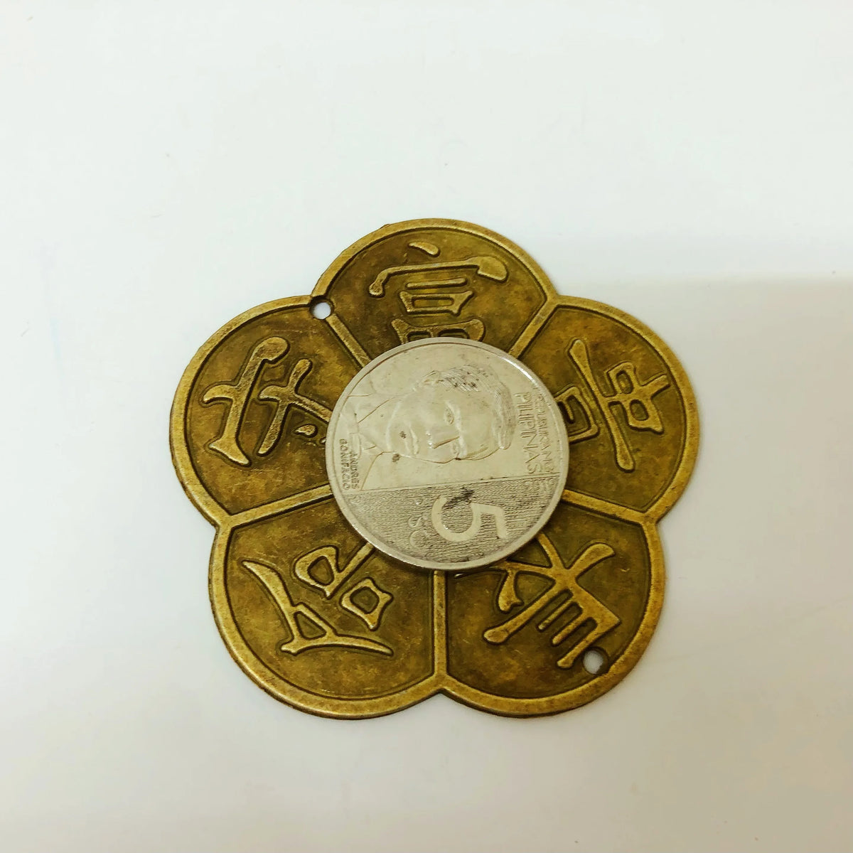 A round brass coin with Chinese characters embossed on its surface, used for Feng Shui and home decor.