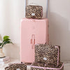 A pink suitcase with a leopard print toiletry bag on top and a matching zippered pouch below.