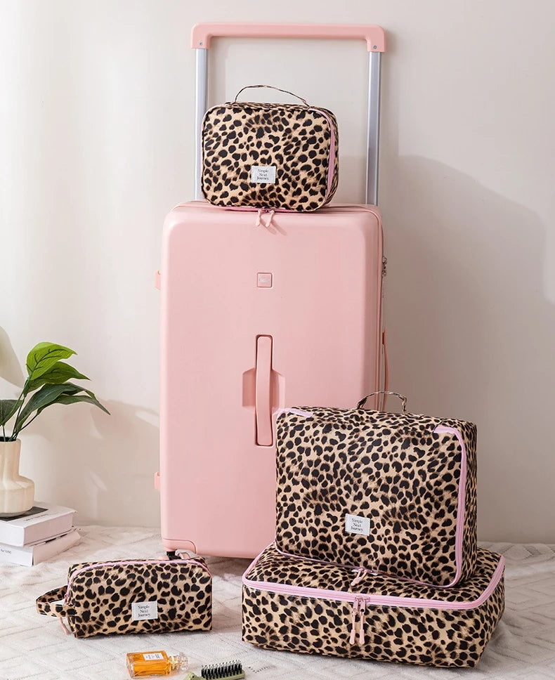 A pink suitcase with a leopard print toiletry bag on top and a matching zippered pouch below.