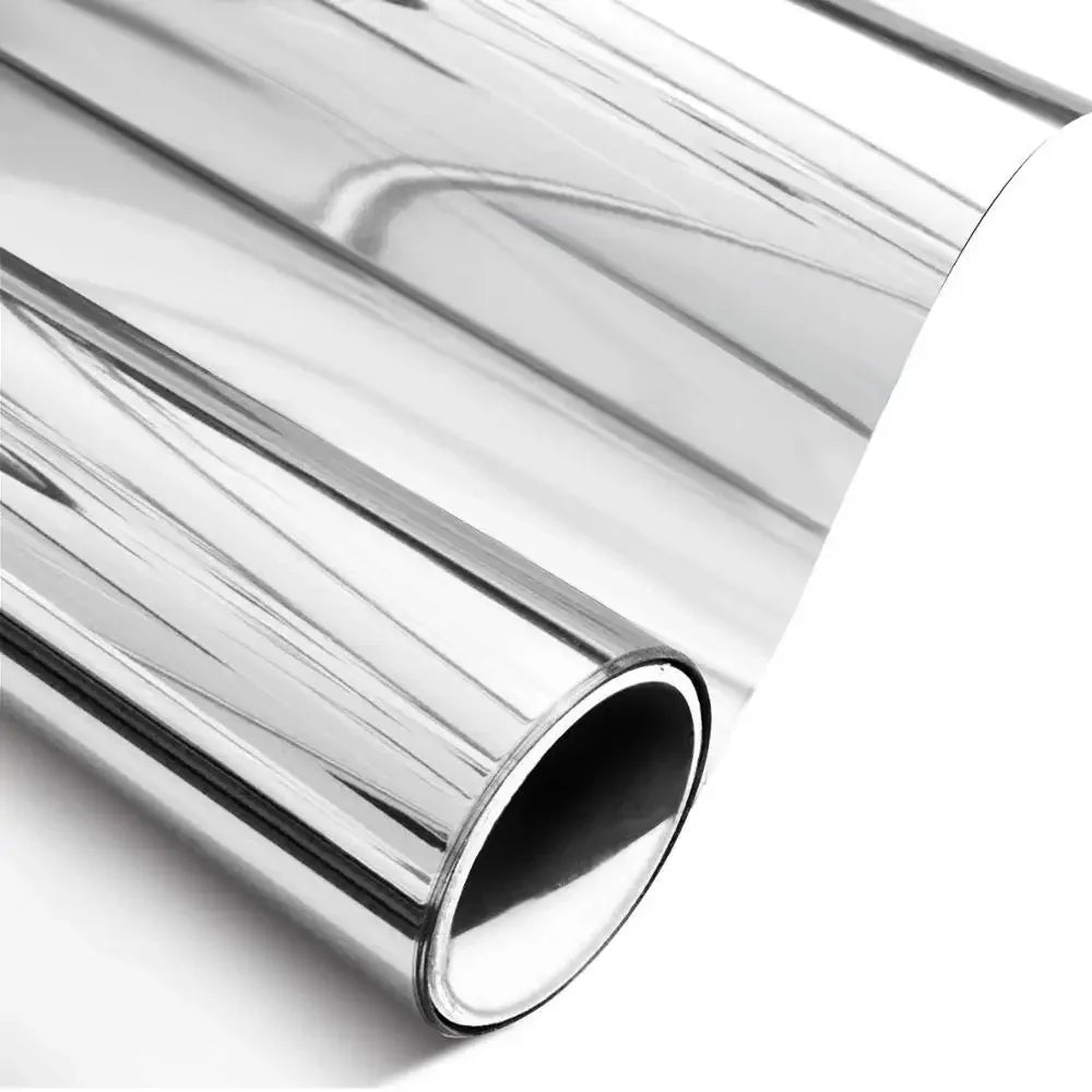 A close-up view of silver one-way mirror window film rolled up, showing its reflective surface.