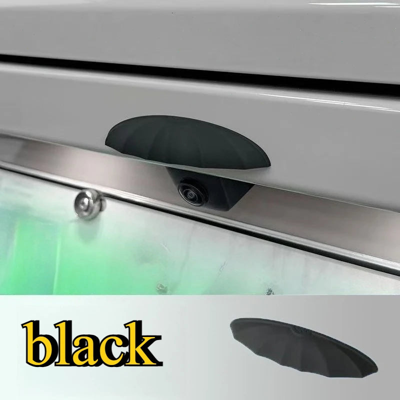 A black rain shield for a universal car rear camera is shown mounted on a vehicle's exterior.
