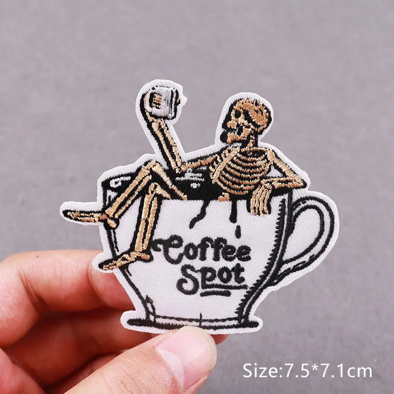 An embroidered patch depicting a skull sitting in a coffee cup, used for DIY clothing decor.