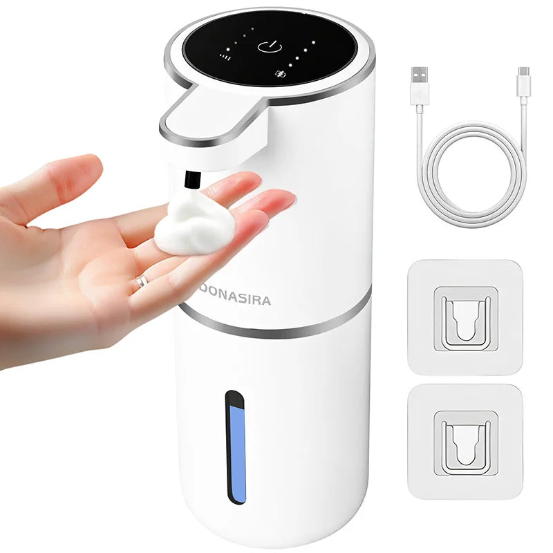 A white touchless automatic soap dispenser is shown being used by a hand, with charging cables and sensor components displaye