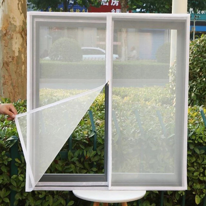 A white self-adhesive window screen mesh with a zipper is shown open in a frame against a green hedge.