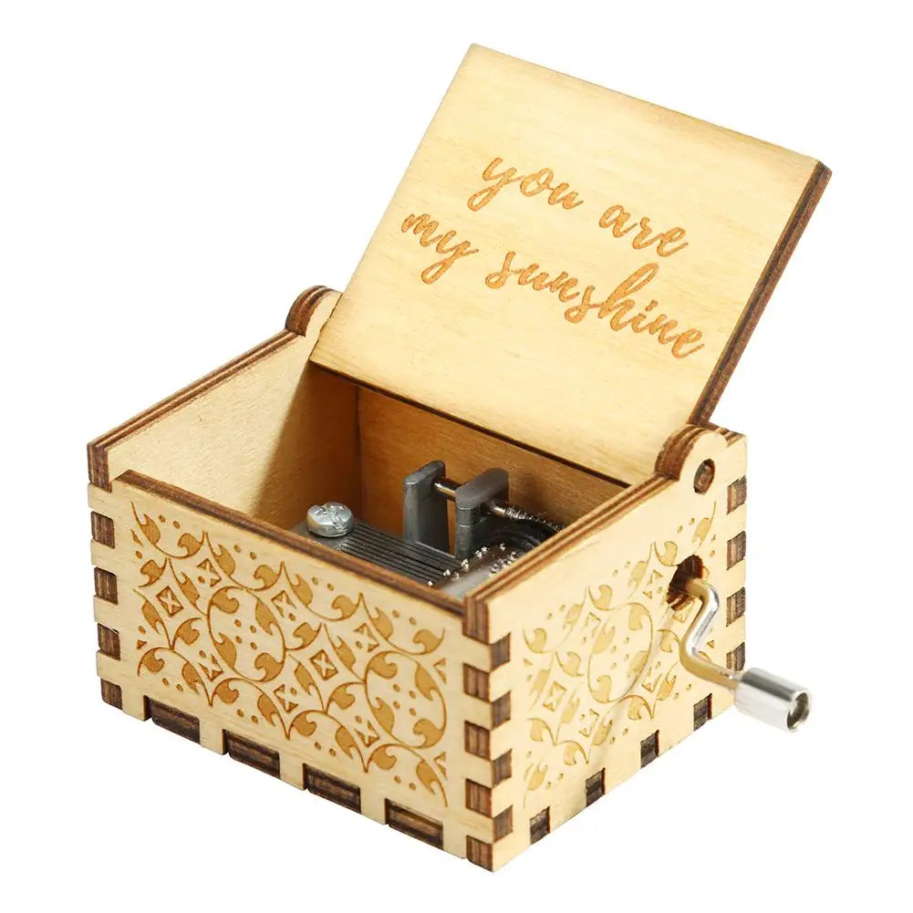 A hand-cranked wooden music box with a lid engraved 'you are my sunshine' and decorative wood carving.