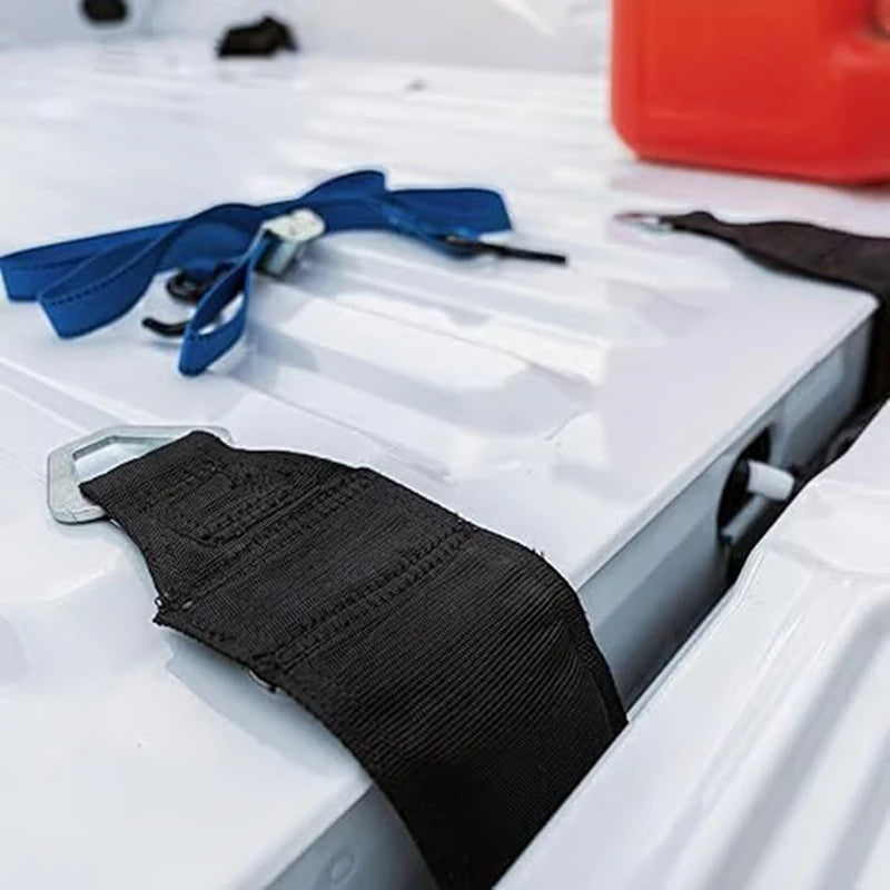 A black tie-down strap and a blue strap are displayed on a white surface.