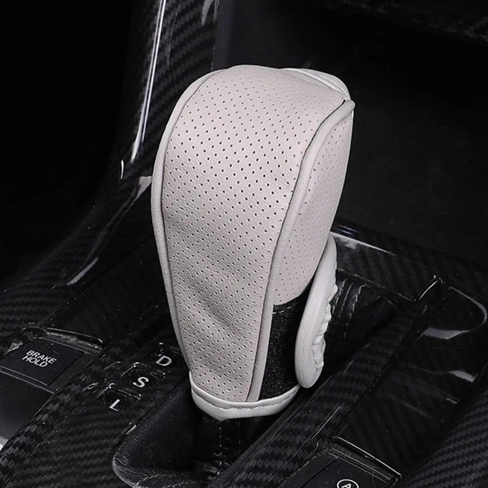 A light gray leather shift knob cover is shown resting on a black gear shift, highlighting its breathable texture.