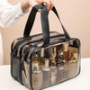A transparent PVC travel toiletry bag with a black strap is being held, showing various glass bottles inside.