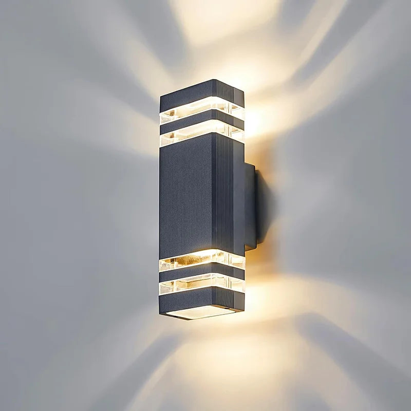 Modern up and down LED wall sconce with a dark gray finish casting light rays on a wall.