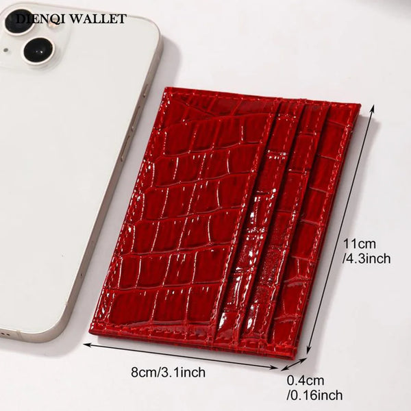 A red crocodile-textured cardholder wallet next to a white smartphone.