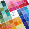 A grid of multicolor acrylic rice beads in various shades and colors stored in a transparent box.