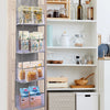 A wooden over-the-door hanging organizer with clear compartments holding various food items and small containers.