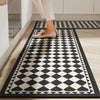 A black and white diamond patterned floor mat is placed on a light wood floor, with a person's legs visible above it.