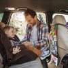 A father is reading a high-contrast crinkle cloth book with a tummy time mirror to his baby in the car.