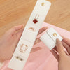 A hand holds a white PU leather jewelry organizer pouch with four compartments, displaying various rings and earrings.