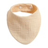 A light beige organic cotton muslin baby bib with an absorbent band around the neck.