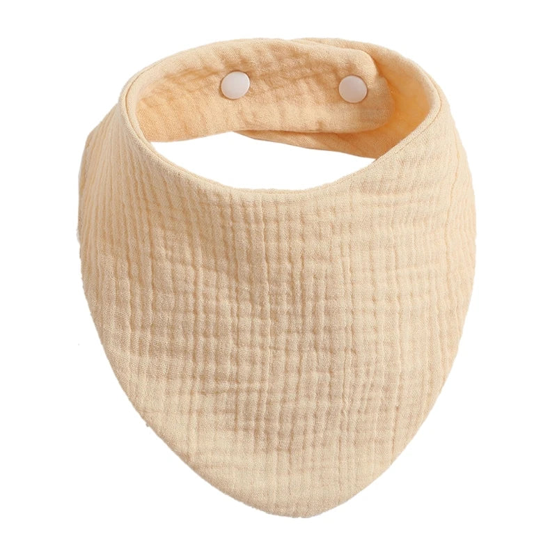 A light beige organic cotton muslin baby bib with an absorbent band around the neck.
