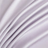 A close-up of a silky soft, light purple bamboo flat sheet draped in flowing folds.